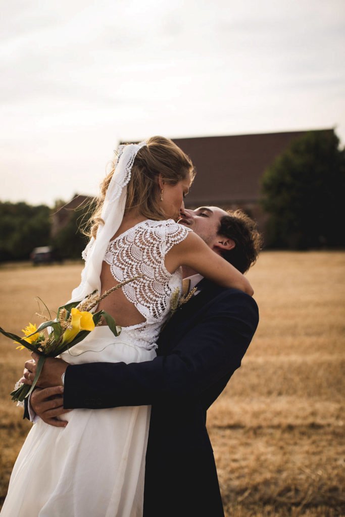 Séance photo de couple de mariage lors d'un coucher de soleil, la mariée dans les bras de son mari
