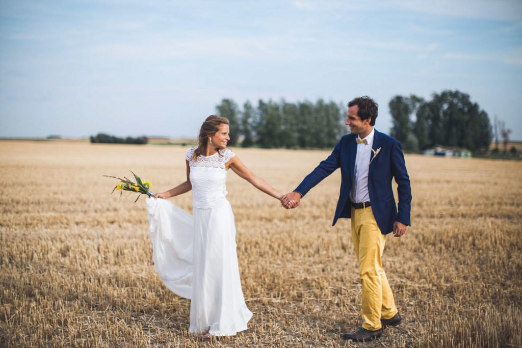 Séance photo de couple de mariés dans les champs lors d'un mariage champêtre