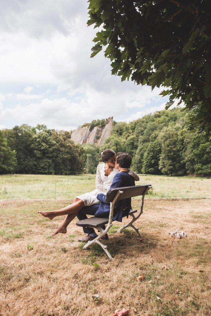 Deux mariés qui s'enlacent sur un banc lors d'une séance photo de couple de mariage par le photographe Maxime du Bus