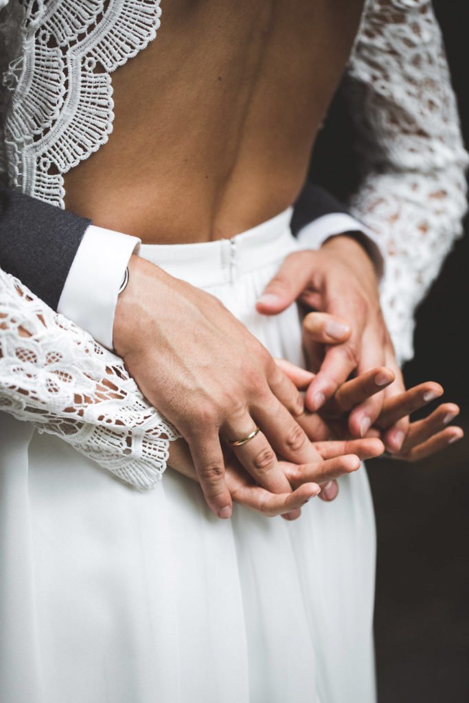 Gros plans sur les mains des mariés lors d'une idée de photo de couple, par le photographe Maxime du Bus