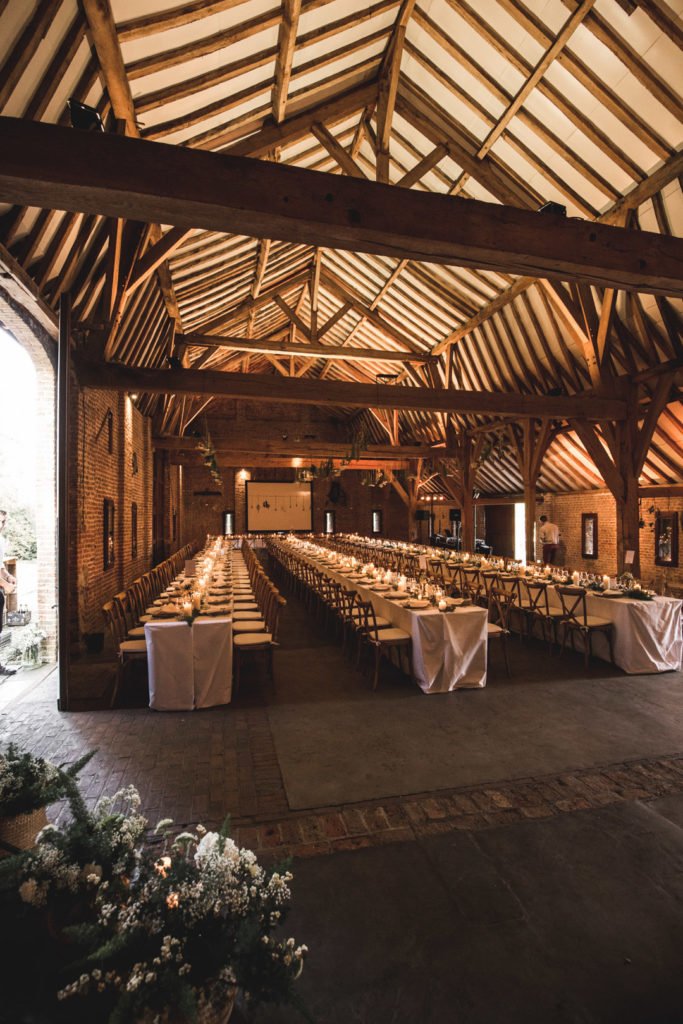 Longues tablées de mariage dans une grange avec des bougies