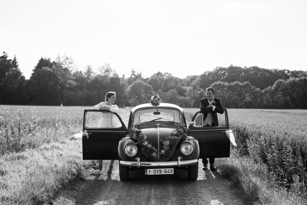 Une photo en noir et blanc lors d'une séance photo de couple de mariés avec une coccinelle, par le photographe Maxime du Bus