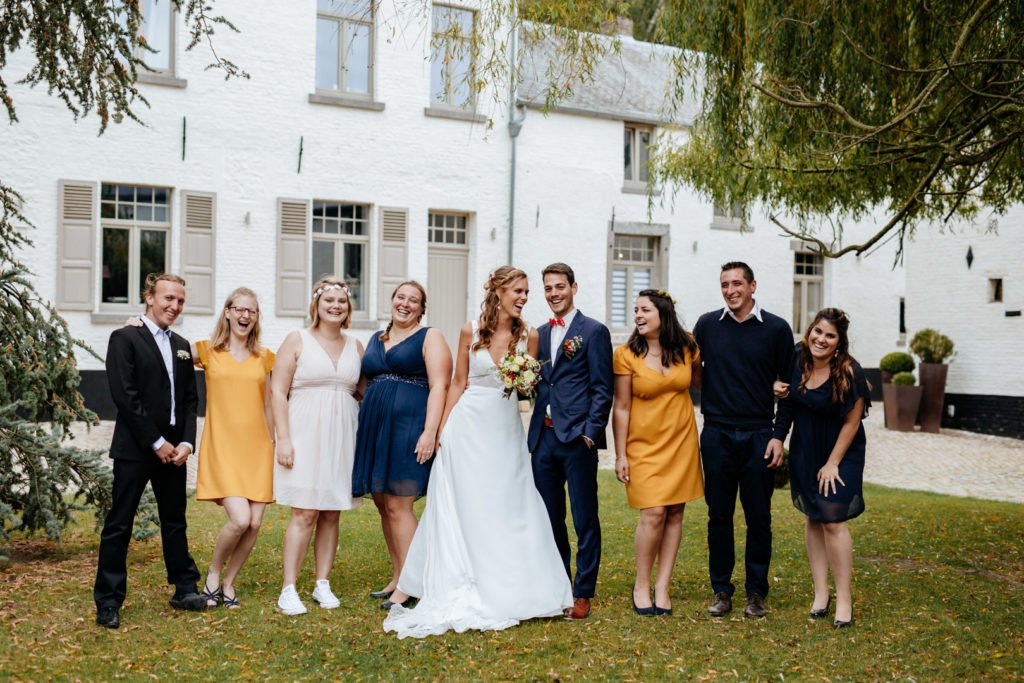 Les témoins de mariage qui posent avec les mariés au milieu dans une cour d'une ferme