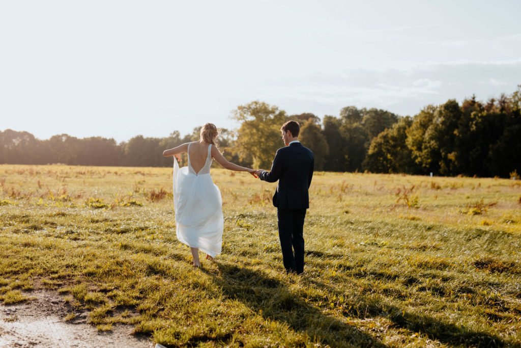 Un couple de mariés qui posent dans les champs lors d'un coucher de soleil