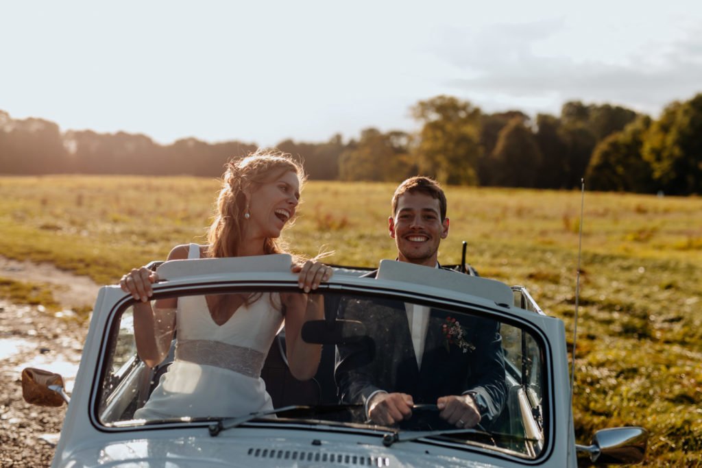 Des mariés dans une deux chevaux lors d'une séance photo de couple