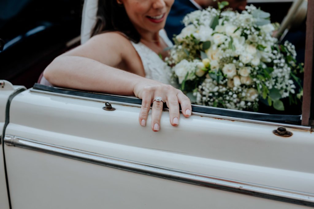 une mariée avec son bouquet de fleur dans la jaguar ancêtre