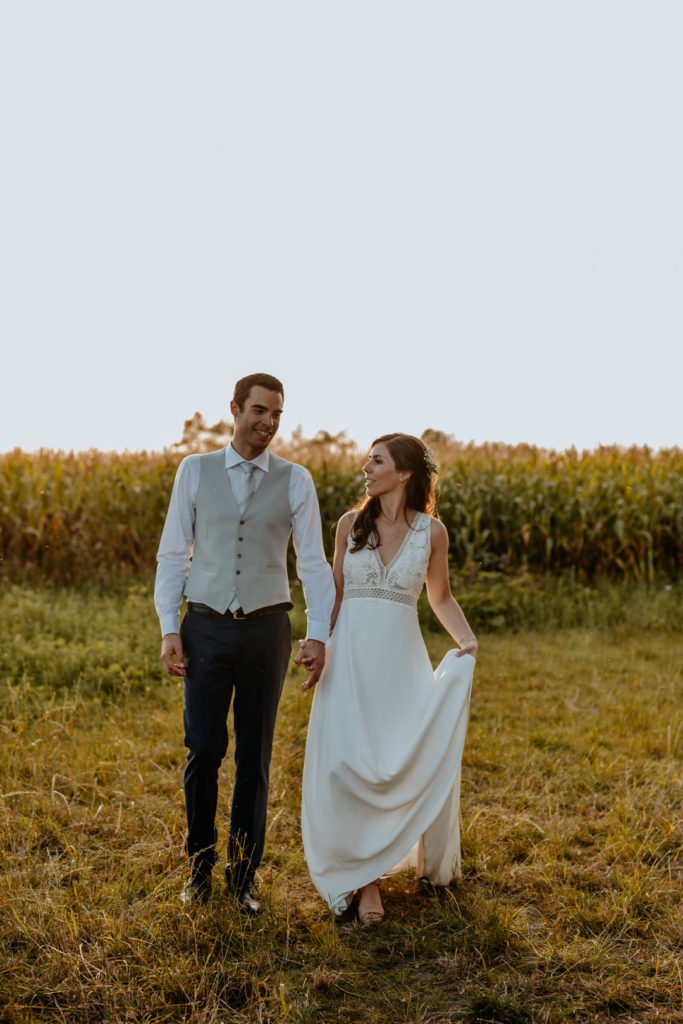 Deux mariés qui se tiennent par la main devant un coucher de soleil