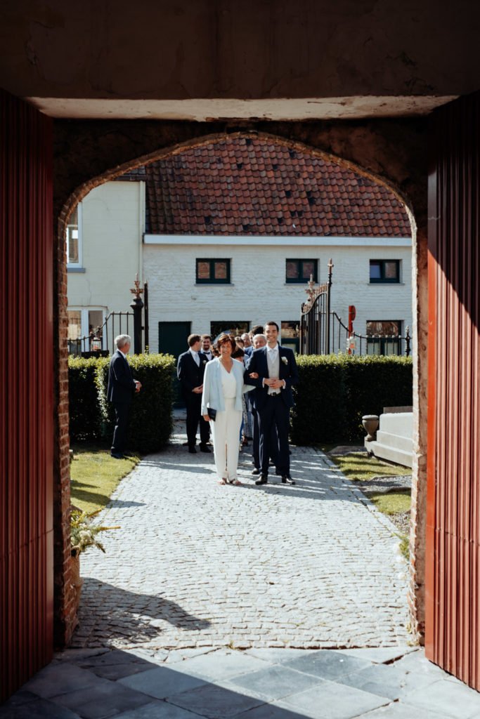 Un marié et sa mère à l'entrée d'une église