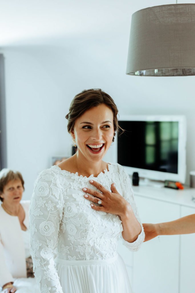 Une mariée souriante avec sa robe de mariée lors des préparatifs